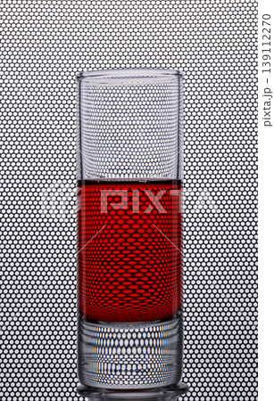A shot glass with a red drink against a background with round holes A shot glass with a red drink against a background with round holes 139112270