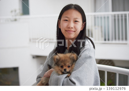 春のマンションの庭で可愛いポメラニアンの子犬と遊んでいる女子中学生の姿 春のマンションの庭で可愛いポメラニアンの子犬と遊んでいる女子中学生の姿 139112976