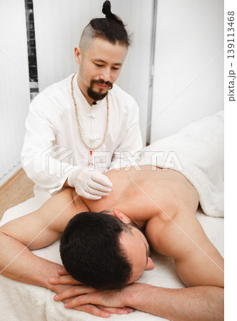 Osteochondrosis treatment with acupuncture. Certified reflexologist treats man back in spa 139113468