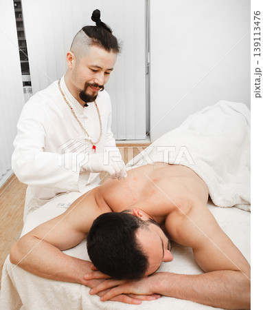 Man on acupuncture procedure for the treatment of back. Traditional chinese medicine Man on acupuncture procedure for the treatment of back. Traditional chinese medicine 139113476
