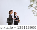 明るいオフィスビルの前で上を見上げる三人の若い女性ビジネスパーソン・就職活動中のリクルートスーツ姿 139113900