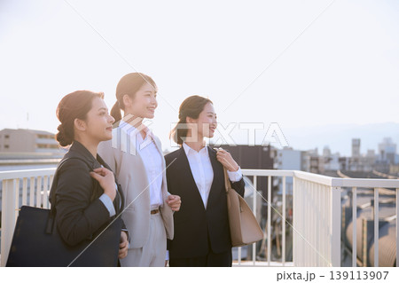 朝の通勤風景・屋外の歩道橋で前向きに微笑む3人の若手女性ビジネスパーソン・スーツ姿の新入社員 朝の通勤風景・屋外の歩道橋で前向きに微笑む3人の若手女性ビジネスパーソン・スーツ姿の新入社員 139113907