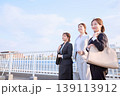 橋の上で前向きに歩く3人の若い女性ビジネスパーソン・スーツ姿のキャリアウーマンと青空 139113912