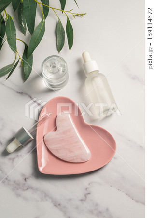 Rose quartz gua sha and oil bottles, abstract beauty photo Rose quartz gua sha and oil bottles, abstract beauty photo 139114572