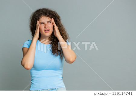 Woman suffering headache stress holding head closing eyes painful tired exhausted facial reaction Woman suffering headache stress holding head closing eyes painful tired exhausted facial reaction 139114741