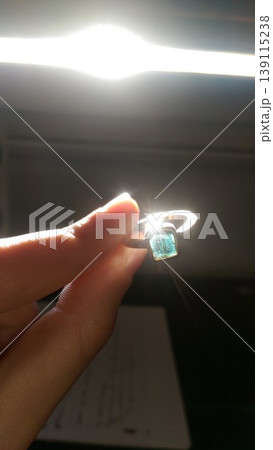 Phone photo of a female hand holding an artisan silver ring with a blue cracked sapphire. Casual jewelry scene showing craftsmanship, detail, and personal style. Phone photo of a female hand holding an artisan silver ring with a blue cracked sapphire. Casual jewelry scene showing craftsmanship, detail, and personal style. 139115238