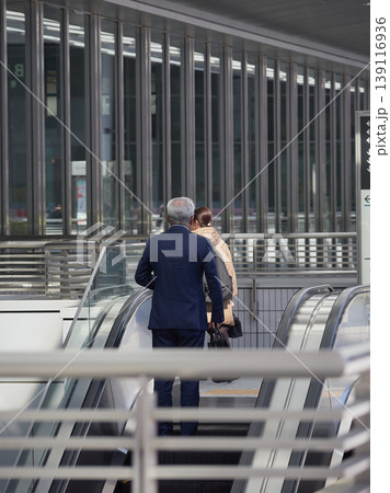 名古屋駅前の商業施設のエスカレーターに登る若い女性と中年男性サラリーマンの姿 139116936