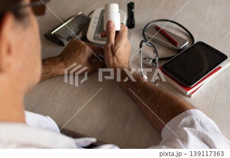 Photo taken from above of a doctor working at his desk.,attending to patients Photo taken from above of a doctor working at his desk.,attending to patients 139117363