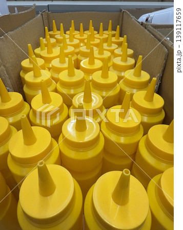 Yellow squeeze bottles arranged in cardboard box from top angle for condiment storage 139117659