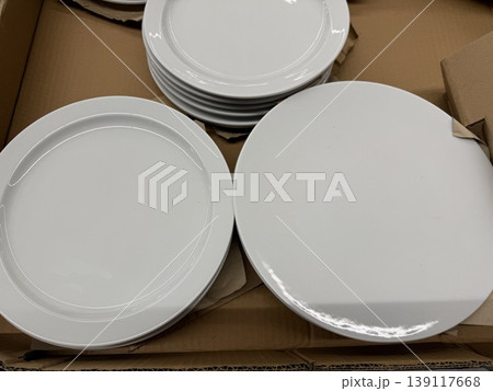 White ceramic plates stacked in a cardboard box, suitable for a kitchen or dining background 139117668