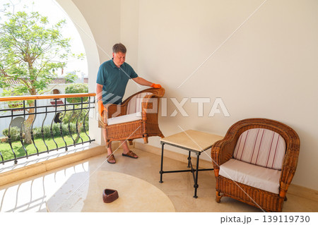 A man rearranges furniture, moves a chair to a new location A man rearranges furniture, moves a chair to a new location 139119730