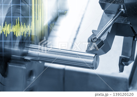 Double exposure of a CNC lathe machine cutting a metal shaft and a digital data graph monitor. 139120120