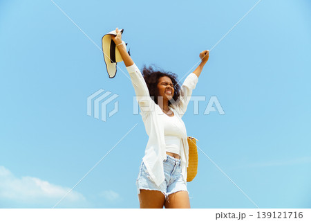 Happy black woman with arms up on summer vacation beach trip 139121716