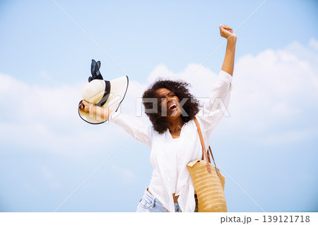 Happy black woman with arms up on summer vacation beach trip 139121718
