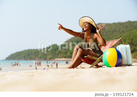 Happy black woman relaxing in deck chair on sunny beach vacation Happy black woman relaxing in deck chair on sunny beach vacation 139121724