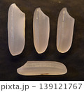 Four grains of uncooked rice, isolated on a dark background. 139121767