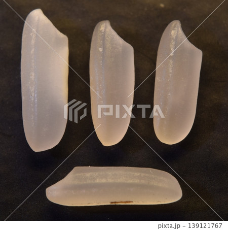 Four grains of uncooked rice, isolated on a dark background. Four grains of uncooked rice, isolated on a dark background. 139121767