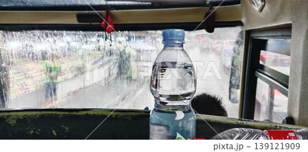 Plastic mineral water bottle inside a public bus during heavy rain with wet windows and traffic jam Plastic mineral water bottle inside a public bus during heavy rain with wet windows and traffic jam 139121909