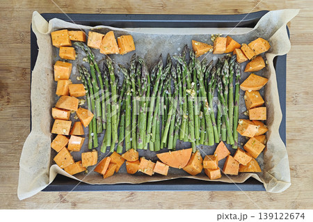 Fresh green asparagus and sweet potato cubes on metal roasting pan, natural light, colorful healthy vegetable dish, view above Fresh green asparagus and sweet potato cubes on metal roasting pan, natural light, colorful healthy vegetable dish, view above 139122674