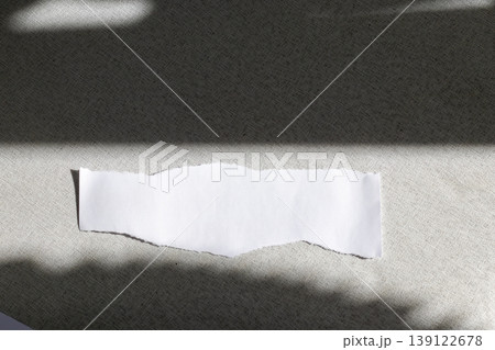 A blank, torn piece of white paper resting on a dark, textured surface 139122678