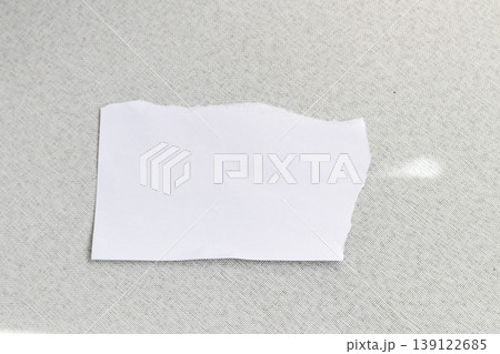 A blank, torn piece of white paper resting on a dark, textured surface 139122685