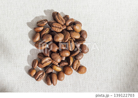 Roasted coffee beans on a textured light fabric like sackcloth Roasted coffee beans on a textured light fabric like sackcloth 139122703