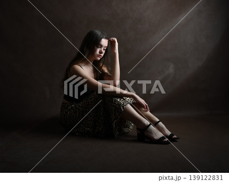 Teenage girl with dark hair is sitting on the studio floor 139122831