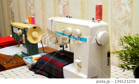 sewing process on a white sewing machine with accessories on the table sewing process on a white sewing machine with accessories on the table 139123259