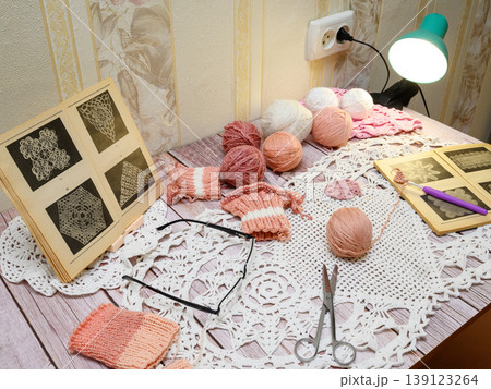 side view of a crochet workspace with yarn balls and patterns side view of a crochet workspace with yarn balls and patterns 139123264