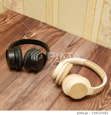 wireless headphones in black and beige colors on a wooden table side view wireless headphones in black and beige colors on a wooden table side view 139123381