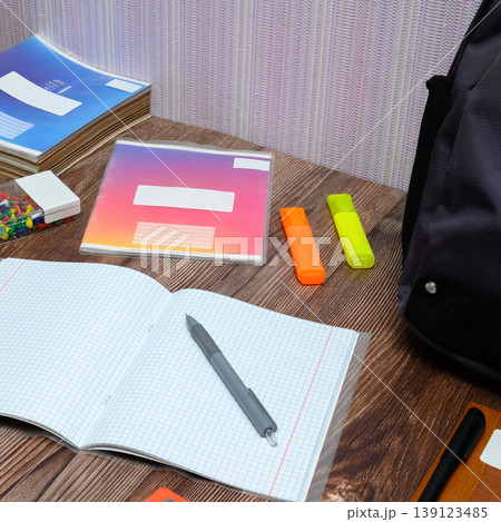 fragment of a student desk with notebooks and bright markers under a backpack 139123485