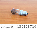 Burnt out T26 E14 bulb for fridges on a wooden table. 139123710