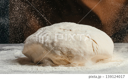 Raw bread dough with flying flour particles on dark background artisan baking process close up food texture 139124017