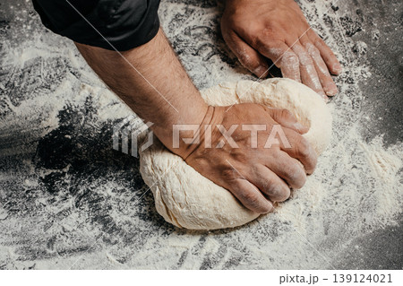 Hands kneading dough on floured surface, artisan bread making process close up Hands kneading dough on floured surface, artisan bread making process close up 139124021