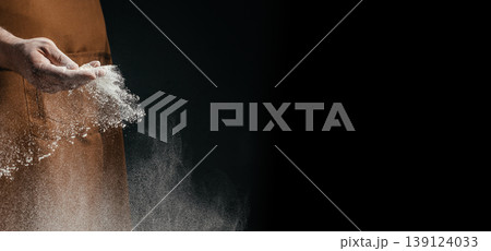 Hand sprinkling flour with falling particles on dark background, baking concept with copy space 139124033