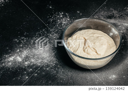 Raw dough in glass bowl on dark background with flour copy space baking concept Raw dough in glass bowl on dark background with flour copy space baking concept 139124042