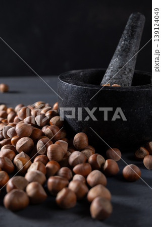 Raw hazelnuts in a stone mortar against a dark background Raw hazelnuts in a stone mortar against a dark background 139124049
