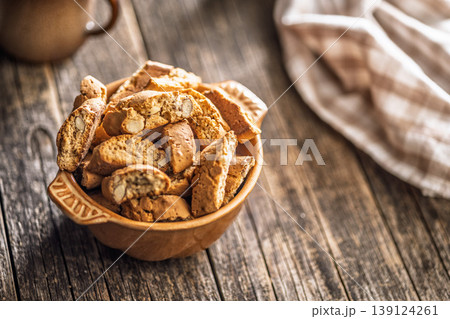 Rustic Almond Biscotti cantuccini in Ceramic Bowl With Coffee Cup on Weathered Wooden Table Rustic Almond Biscotti cantuccini in Ceramic Bowl With Coffee Cup on Weathered Wooden Table 139124261