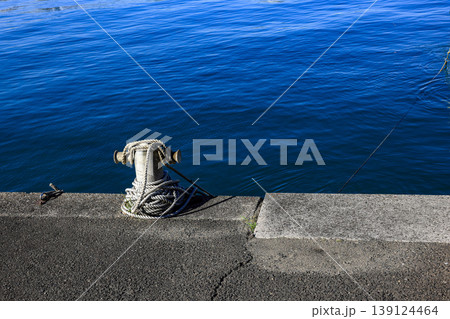 Mooring line on rusty pier referred to a post on a ship or quay. Mooring line on rusty pier referred to a post on a ship or quay. 139124464