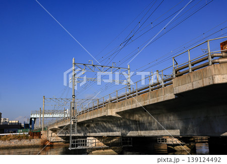 A concrete railway bridge with massive pillars stretching across Murasaki river, Japan. 139124492