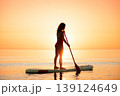 Young woman walking on stand up paddle sup boards by the sea during summer vacation 139124649
