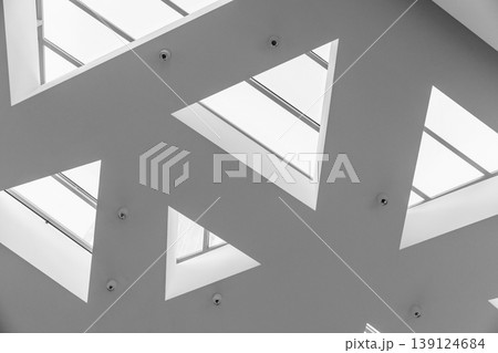 Minimal modern ceiling design with triangular skylights creating a geometric pattern Minimal modern ceiling design with triangular skylights creating a geometric pattern 139124684