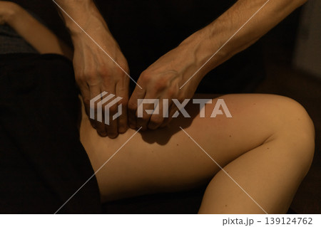 Professional massage therapist working on a woman's upper thigh Professional massage therapist working on a woman's upper thigh 139124762