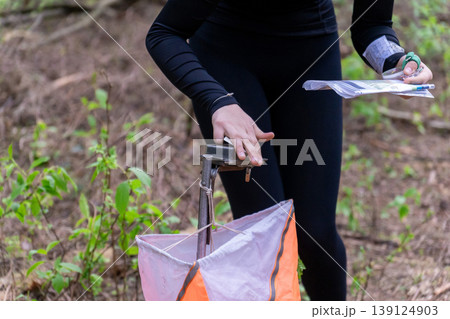 Athlete punches electronic timing device at orienteering control point Athlete punches electronic timing device at orienteering control point 139124903