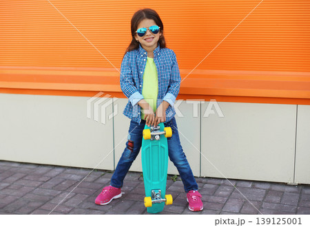 Stylish girl child with skateboard posing in the city Stylish girl child with skateboard posing in the city 139125001