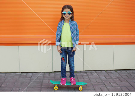 Stylish girl child with skateboard posing in the city 139125004