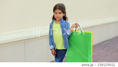 Little girl child with shopping bags posing on city street Little girl child with shopping bags posing on city street 139125012