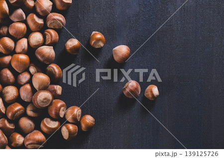 Raw hazelnuts in a stone mortar against a dark background. 139125726