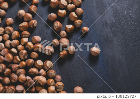 Raw hazelnuts in a stone mortar against a dark background. Raw hazelnuts in a stone mortar against a dark background. 139125727
