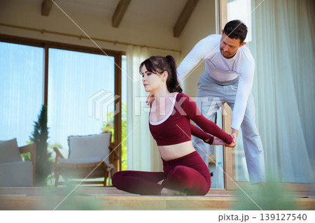 Personal instructor helping woman with correct body alignment on terrace Personal instructor helping woman with correct body alignment on terrace 139127540